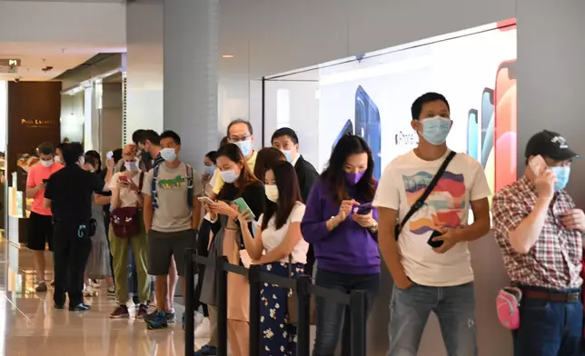 蘋果店工作人員在疫情下呼籲排隊者保持社交距離。