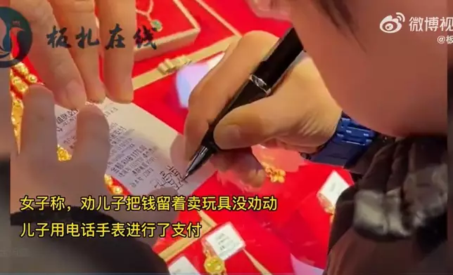 小朋友有模有樣地在單據上簽名，十分可愛（影片截圖）