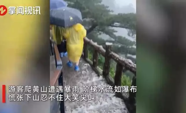 遊客擔遮身著雨衣（影片截圖）