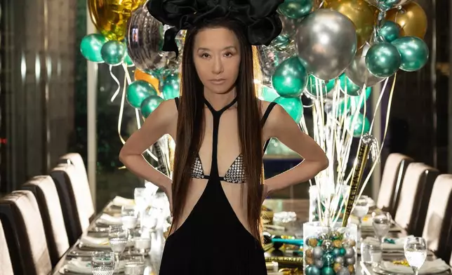 Vera Wang頭戴一個巨型蝴蝶結髮飾，上身穿著閃閃比基尼搭配一件吊帶長裙