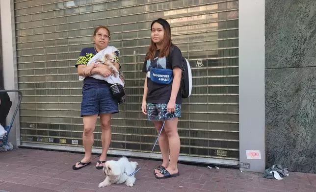 住在華豐大廈15樓徐太及囡囡抱住兩愛犬，向記者憶述逃生時的驚險場面。(巴士的報記者攝)