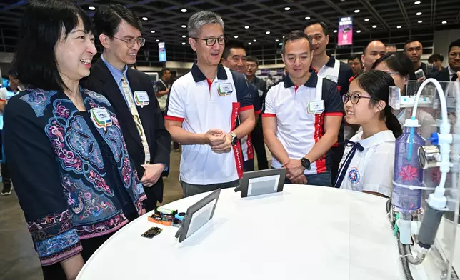 高小組冠軍得主向警務處處長蕭澤頤（左三）、中國銀行（香港）資訊科技部總經理翁暉（左二）、教育局常任秘書長李美嫦（左一）及警務處副處長（行動）周一鳴（右二）介紹得奬作品。政府新聞處圖片