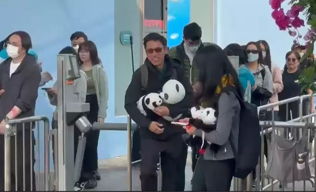 早前受訪的陳先生更大展笑容，揮動手中的熊貓公仔與傳媒打招呼！(巴士的報記者攝)