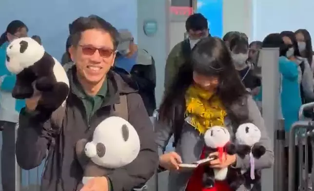早前受訪的陳先生更大展笑容，揮動手中的熊貓公仔與傳媒打招呼！(巴士的報記者攝)