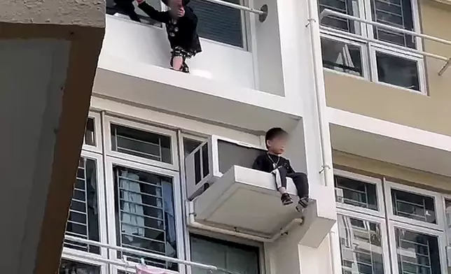 粉嶺皇后山邨皇樂樓一個單位，有兩名幼童分別危坐大廈外牆及冷氣機窗台，警員伸手救回其中一名男童回到屋內。網上圖片