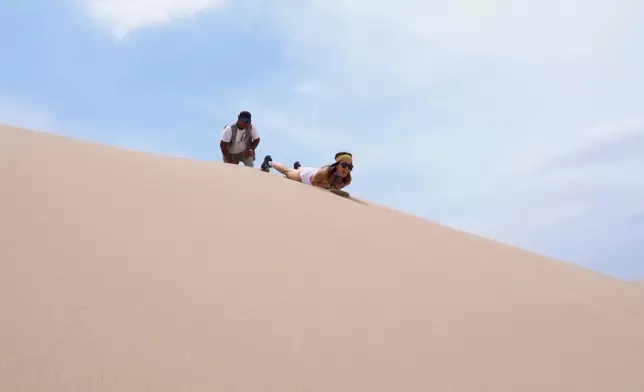 挑戰垂直趴在滑板上體驗高處滑沙。