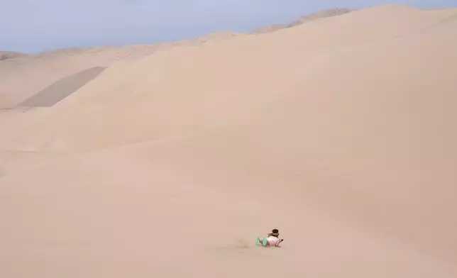 挑戰垂直趴在滑板上體驗高處滑沙。