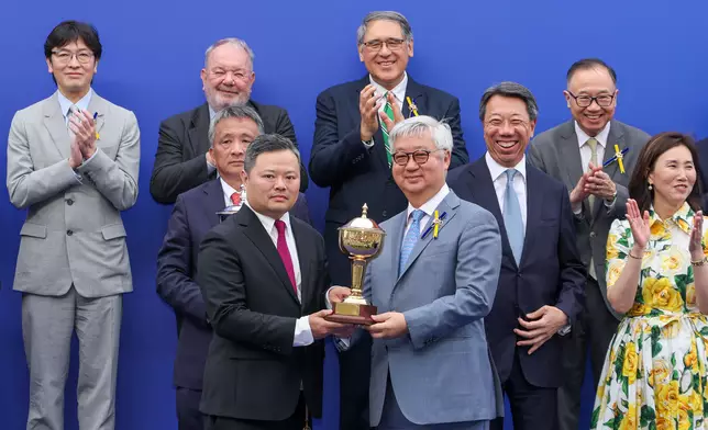 馬會董事楊紹信博士（右）在頒獎禮上將小型獎盃頒予「遨遊氣泡」的馬主日月輝煌賽馬團體代表程俊華。香港賽馬會圖片