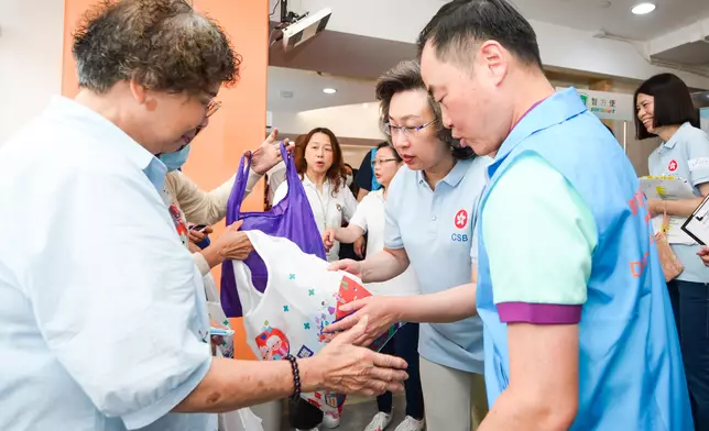 楊何蓓茵（前排右二）和數字政策專員黃志光（前排右一）與公務員義工向長者派發禮物包。 政府新聞處圖片