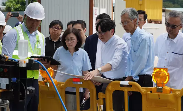 發展局局長甯漢豪（前排左二）在坪輋路聽取水務署署長黃恩諾（前排左三）介紹如何使用先進科技探測水管內的情況。 政府新聞處圖片