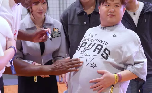 肥仔伸出肚⼦示意簽名位置。