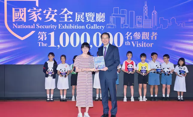 維護國家安全委員會秘書長區志光（前排右）向國家安全展覽廳第100萬名參觀者代表頒發紀念證書。第100萬名參觀者是保良局陸慶濤小學的三年級學生。 政府新聞處圖片