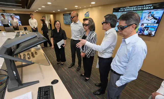 楊何蓓茵（右三）聽取有關數碼航空照片解讀系統的介紹，除了供政府部門和相關機構從遠端搜尋、閱覽和分析高解析度三維資料，更可讓專業人員繪製和檢視三維地形圖。旁為公務員事務局常任秘書長梁卓文（右一）及土拓署署長方學誠（右四）。 政府新聞處圖片