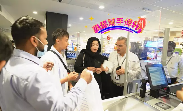 超市經理帶梁彥宗和練美娟到收銀處結帳。