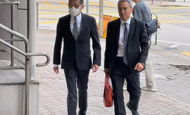 被告陳燿陽（左）和辯方資深大律師梁卓然（右）一起走入東區裁判法院。巴士的報記者攝