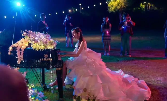 Yumi換上華麗晚裝坐在三角鋼琴面前自彈自唱。