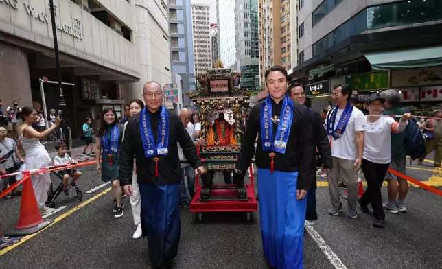 東華三院主席何猷啟（前排右）和副主席曾慶業（前排左）聯同董事局成員隨文武二帝鑾輿出巡，吸引途人及遊客駐足觀賞。