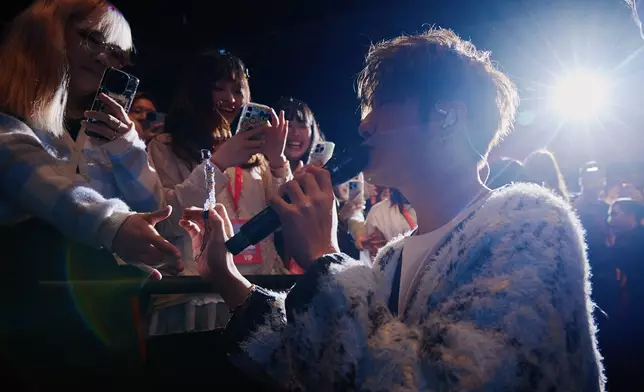 一邊演唱《半天空檔》，一邊與歌迷握手、打招呼走上舞台。