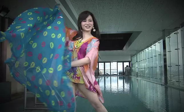 跟住有花俏斗篷式泳衣外搭、配「撞色」朱唇披肩。