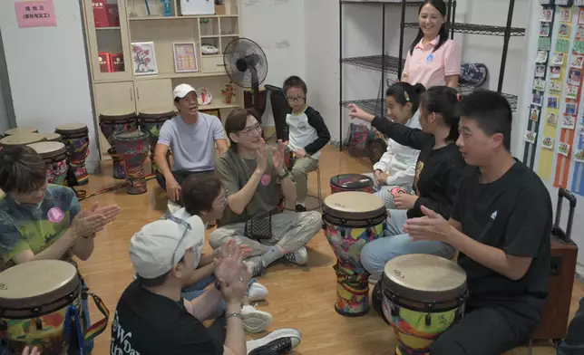 何啟南、胡渭康與孩子一起打非洲鼓。