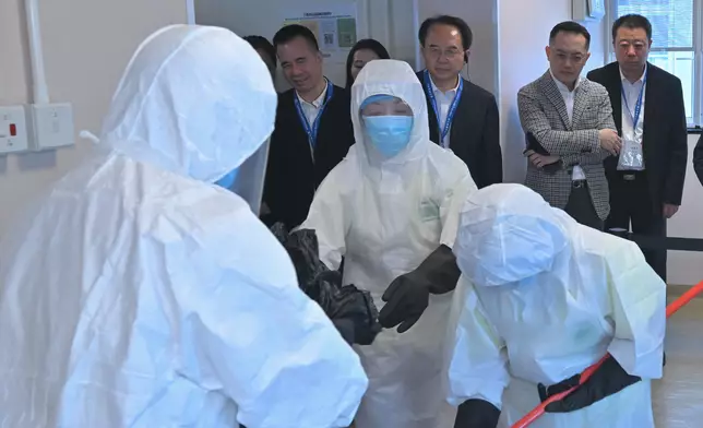 食物環境衞生署人員進行清潔和消毒程序。衞生署署長林文健（後排右二）和多位觀察員在旁視察。 政府新聞處圖片