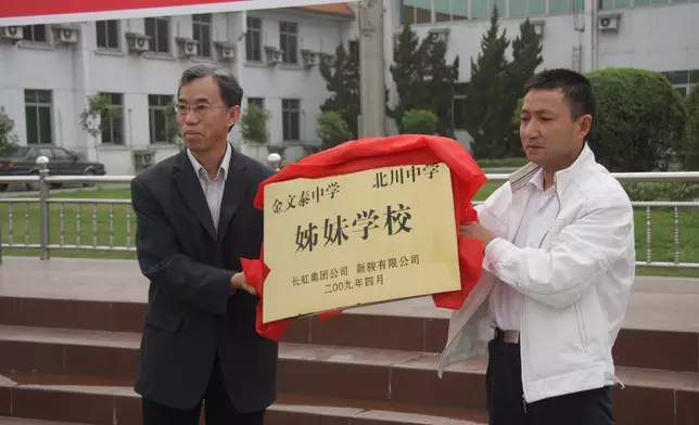 金文泰中學李國佳校長(左)和北川中學劉亞春校長(右)舉起四川長虹和香港新駿合赠的「姊妹学校」銅牌。楊向杰供相