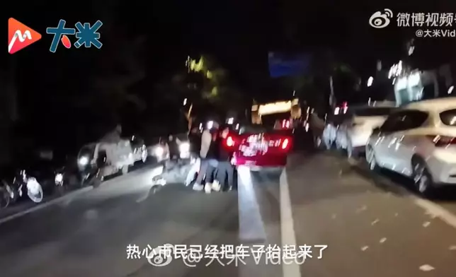 電單車騎士被捲入車底獲逾20名熱心途人合力抬車2分鐘平安救出。影片截圖
