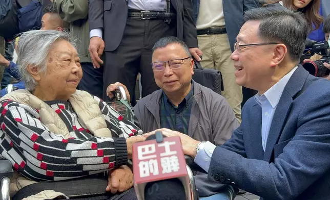 李家超期間蹲下與長者李太(坐輪椅者)及她兒子李生(中)傾談，並祝對方身體健康。巴士的報記者攝