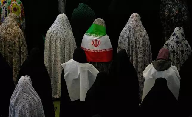 2026年3月21日周六，伊朗信徒在伊朗德黑蘭的伊瑪目霍梅尼大清真寺（Imam Khomeini Grand Mosque）進行開齋節祈禱，標誌著齋戒月結束，其中一人身穿伊朗國旗。(美聯社圖片/Vahid Salemi) AP圖片