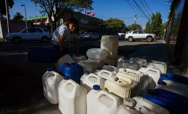 2026年3月24日周二，智利聖地亞哥，一名女子在司機排隊入油時，售賣盛載燃料的紙箱。(美聯社圖片/Esteban Felix) AP圖片