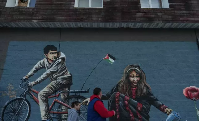 2026年2月27日周五，新澤西州帕特森南帕特森社區主街上，被命名為「巴勒斯坦之路」的路段，行人走過一幅壁畫前，當時正值齋戒月。(美聯社圖片/Luis Andres Henao) AP圖片