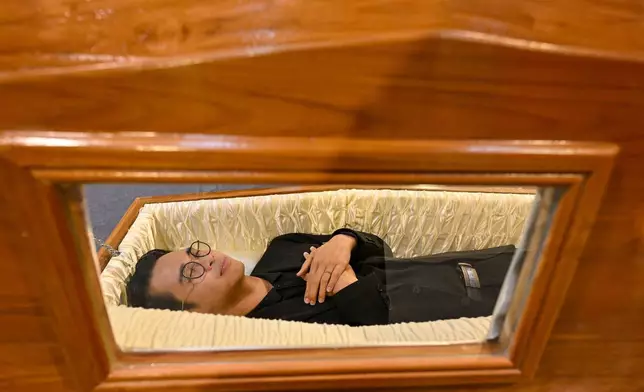 2026年3月13日周五，一名參觀者在泰國暖武里府的「死亡節」中試用棺材。(美聯社圖片/Kittinun Rodsupan) AP圖片