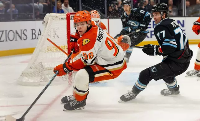 安納罕鴨隊後衛帕維爾明秋科夫（Pavel Mintyukov）（98號）在2026年3月20日周五於鹽湖城舉行的一場國家冰球聯盟（NHL）賽事第一節期間，帶球對抗猶他猛獁隊右翼JJ彼得卡（JJ Peterka）（77號）。(美聯社圖片/Melissa Majchrzak) AP圖片