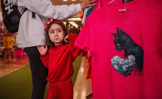 一名兒童在羅馬尼亞布加勒斯特舉行的「貓咪奧斯卡」國際貓咪選美大賽上，看到出售的T恤時露出鬼臉。該比賽於2026年3月21日（周六）舉行，吸引逾200隻貓咪參與。(美聯社圖片/Vadim Ghirda) AP圖片