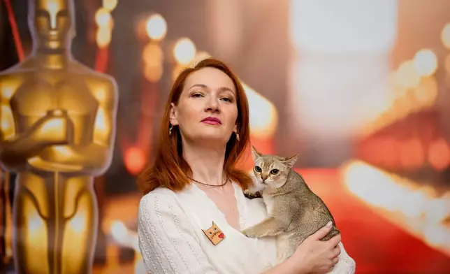 一名女子在羅馬尼亞布加勒斯特舉行的「貓咪奧斯卡」國際貓咪選美大賽上，抱著一隻新加坡貓在奧斯卡主題的拍照背景前擺姿勢。該比賽於2026年3月21日（周六）舉行，吸引逾200隻貓咪參與。(美聯社圖片/Andreea Alexandru) AP圖片