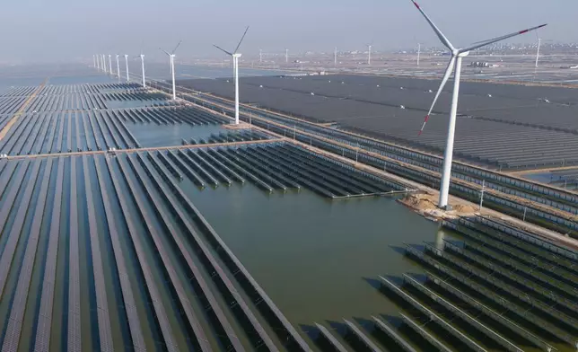 資料圖片：2024年3月22日，中國東部山東省（Shandong province）濰坊（Weifang）附近的一個太陽能農場旁，風力渦輪機正在運作。(美聯社圖片/Ng Han Guan) AP圖片
