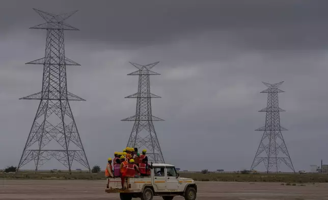 資料圖片：2023年9月21日，印度古吉拉特邦（Gujarat）西部，印度與巴基斯坦邊境附近的布吉區（Bhuj district）卡夫達（Khavda）鎮，卡里姆沙希村（Karim Shahi village）的鹽漠中，工人乘坐車輛前往阿達尼綠色能源有限公司（Adani Green Energy Limited）再生能源園區的建築工地。(美聯社圖片/Rafiq Maqbool) AP圖片