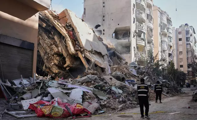 真主黨成員走過黎巴嫩貝魯特南部郊區達希耶一幢遭以色列空襲摧毀的建築物。攝於2026年3月5日周四。(美聯社圖片/Hassan Ammar) AP圖片