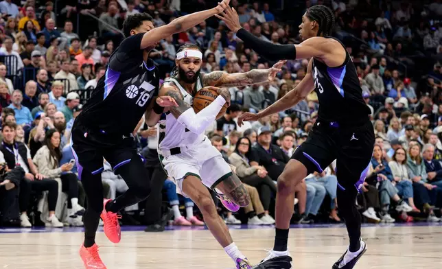 密爾沃基公鹿後衛小加利特倫特（中）在周四（2026年3月19日）於鹽湖城舉行的一場NBA籃球賽上半場，在猶他爵士後衛艾斯拜利（左）及前鋒高迪威廉斯（右）防守下，運球上籃。（美聯社圖片/Tyler Tate） AP圖片