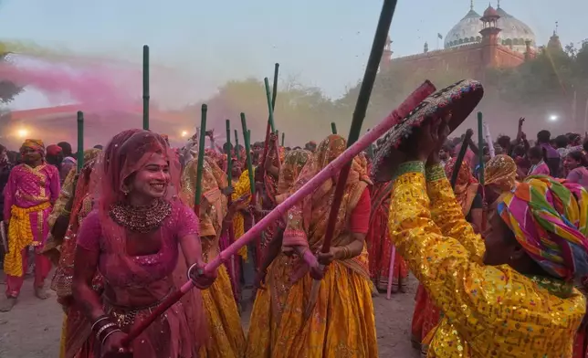 2026年2月27日，印度馬圖拉，灑紅節慶祝活動期間，一名跨性別社群成員與其他女性信眾在室利克里希納誕生地廟建築群內，象徵性地用木棍擊打男性，以慶祝棍棒灑紅節（Lathmar Holi）。(美聯社圖片/Manish Swarup) AP圖片