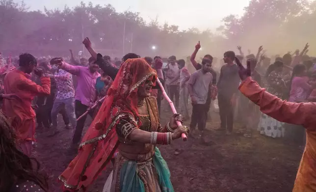 2026年2月27日，印度馬圖拉，灑紅節慶祝活動期間，一名跨性別社群成員在室利克里希納誕生地廟建築群內跳舞時，驅趕狂歡者。(美聯社圖片/Manish Swarup) AP圖片