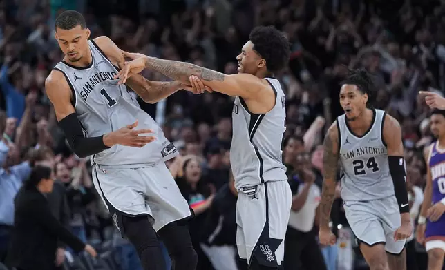 聖安東尼奧馬刺隊前鋒文班亞馬（Victor Wembanyama）（1號）在2026年3月19日周四於聖安東尼奧舉行的一場NBA籃球賽最後幾秒射入致勝一球後，獲隊友後衛迪倫夏柏（Dylan Harper）（中）及後衛戴雲華素（Devin Vassell）（24號）慶祝。(美聯社圖片/Eric Gay) AP圖片