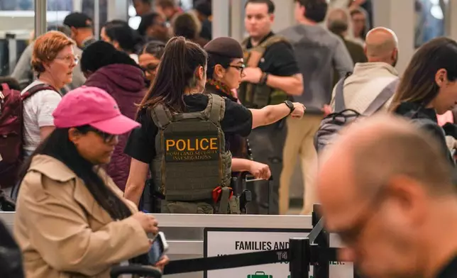 2026年3月23日周一，一名聯邦移民官員在紐約皇后區甘迺迪國際機場（John F. Kennedy International Airport）的安檢站協助運輸安全管理局人員。(美聯社圖片/Ryan Murphy) AP圖片