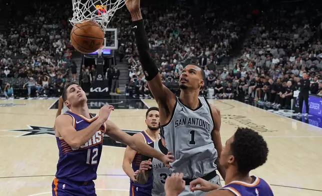 2026年3月19日，聖安東尼奧馬刺前鋒維克多·文班亞馬（Victor Wembanyama）（1號）在NBA籃球賽下半場，在鳳凰城太陽後衛科林吉利斯比（Collin Gillespie）（12號）頭上得分。攝於聖安東尼奧。（美聯社圖片/Eric Gay） AP圖片