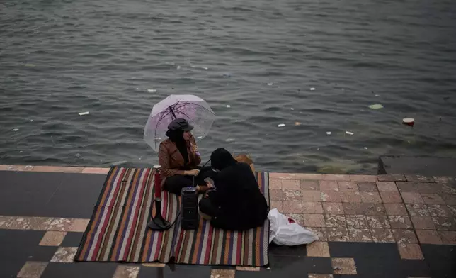 婦女們坐在伊拉克巴士拉的阿拉伯河（Shatt al-Arab River）濱海大道旁。攝於2026年3月26日周四。(美聯社圖片/Leo Correa) AP圖片