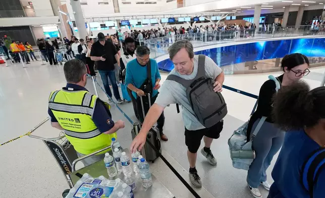 2026年3月27日周五，一名旅客在侯斯頓（Houston）喬治布殊洲際機場（George Bush Intercontinental Airport）的安檢站排隊時，伸手領取派發的樽裝水。(美聯社圖片/David J. Phillip) AP圖片