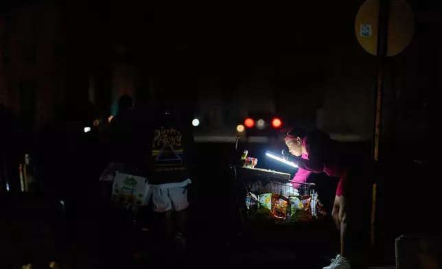 2026年3月21日周六，古巴哈瓦那，一名小販在馬雷貢海濱大道上，以電池燈照明等待顧客。(美聯社圖片/Ramon Espinosa) AP圖片