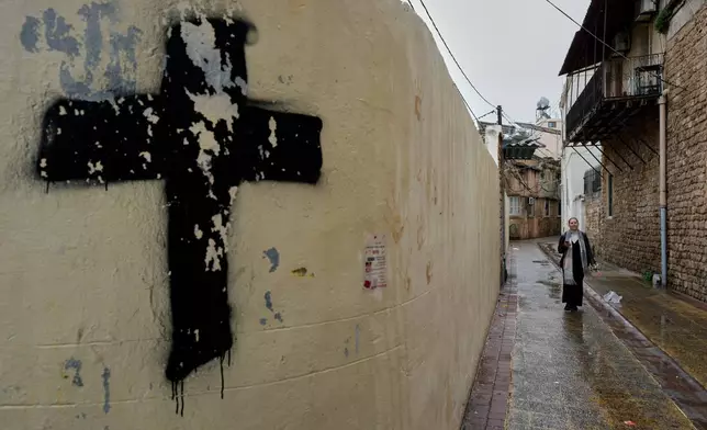 2026年3月29日周日，在黎巴嫩南部港口城市泰爾，一名婦女走在其中一條基督徒巷道上，前往聖湯瑪斯大教堂參與棕枝主日彌撒。(美聯社圖片/Hussein Malla) AP圖片