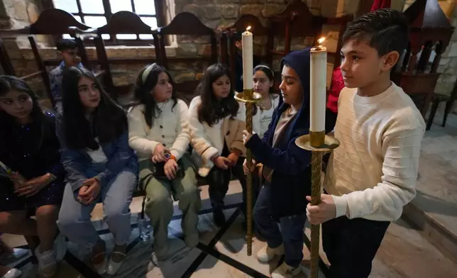 2026年3月29日，周日，黎巴嫩南部港口城市提爾（Tyre）的聖湯瑪斯大教堂（Saint Thomas Cathedral），男孩們在棕枝主日彌撒遊行中手持蠟燭。(美聯社圖片/Hussein Malla) AP圖片