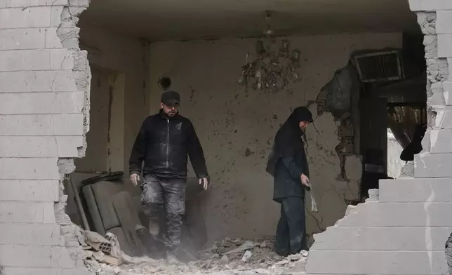 2026年3月15日周日，在伊朗德黑蘭，人們清理公寓內的碎片。該公寓在周五美國與以色列的襲擊中，因附近警局被擊中而受損。(美聯社圖片/Vahid Salemi) AP圖片